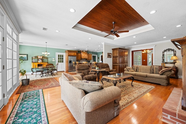 4155 Quail Run Cir, Valdosta, GA 31601 - living area featuring a chandelier, a tray ceiling, light wood-style floors, ornamental molding, and a ceiling fan