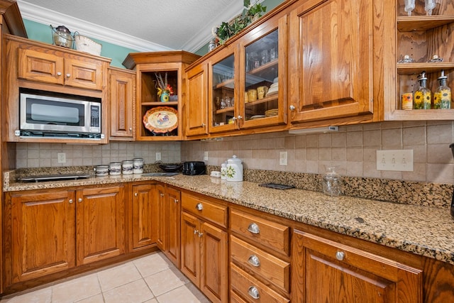 4155 Quail Run Cir, Valdosta, GA 31601 - kitchen with stainless steel microwave, open shelves, ornamental molding, brown cabinetry, and a textured ceiling