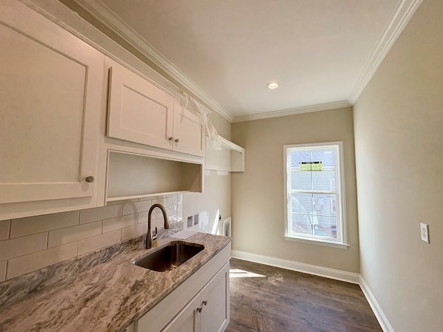 kitchen featuring decorative backsplash, baseboards, light stone counters, and a sink