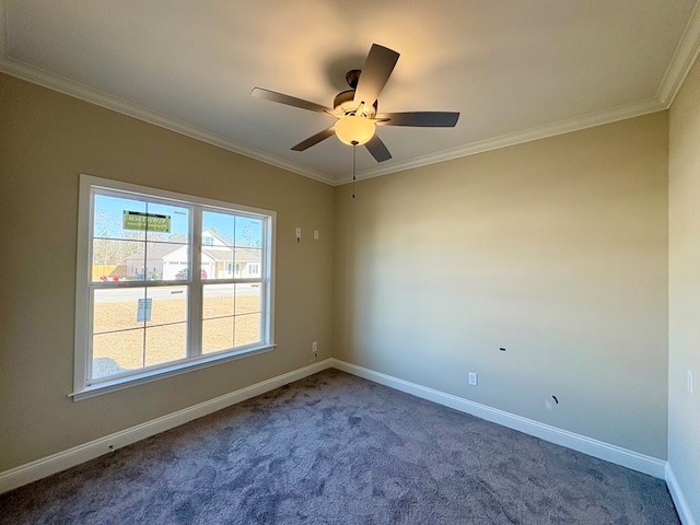 carpeted spare room featuring ornamental molding, baseboards, and a ceiling fan