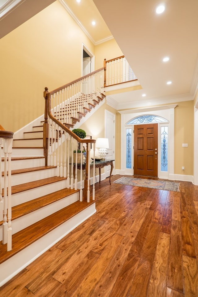 foyer entrance featuring stairs, crown molding, baseboards, and wood finished floors