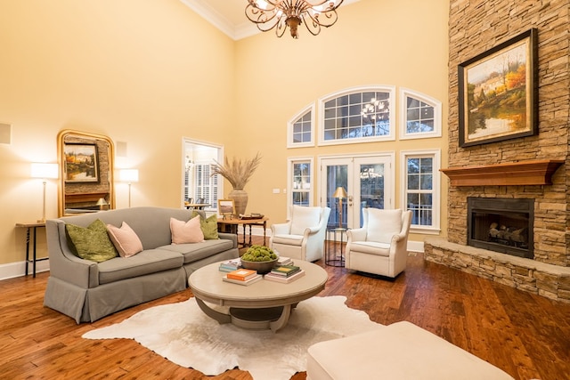 living room featuring ornamental molding, wood finished floors, french doors, a fireplace, and a chandelier