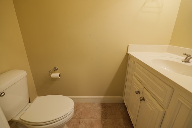 half bathroom featuring toilet, baseboards, and vanity