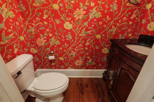 bathroom with vanity, wood finished floors, toilet, and wallpapered walls