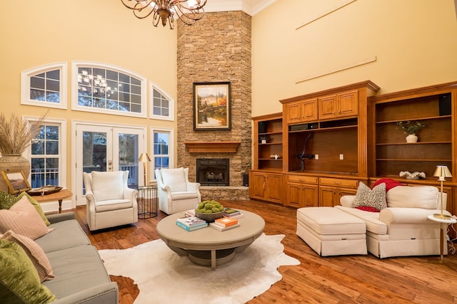 living area with an inviting chandelier, a fireplace, wood finished floors, and french doors