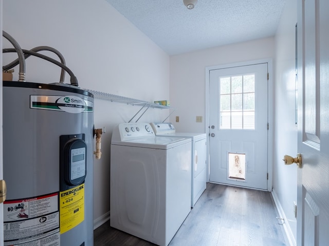 laundry room featuring light hardwood / wood-style floors, washing machine and dryer, water heater, and a textured ceiling