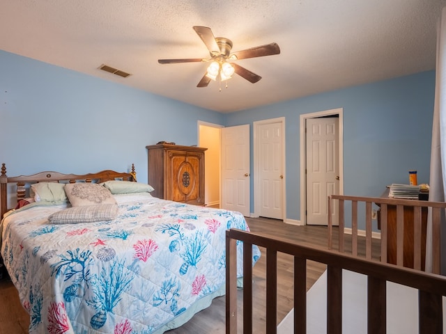 bedroom with dark hardwood / wood-style flooring, a textured ceiling, and ceiling fan