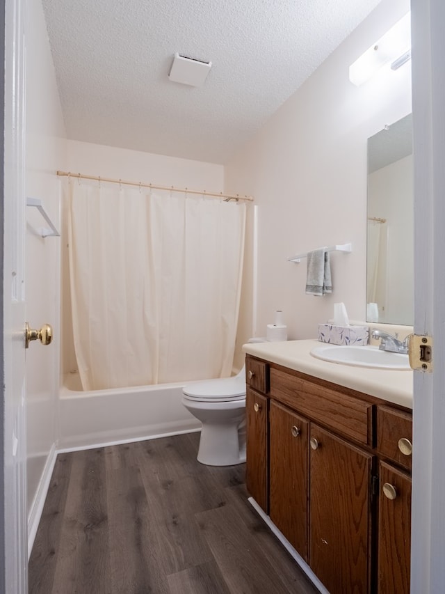 full bathroom with shower / tub combo with curtain, hardwood / wood-style flooring, vanity, toilet, and a textured ceiling