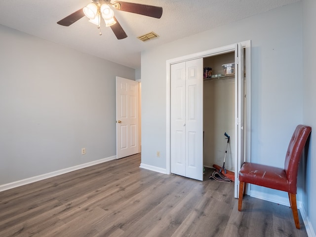 unfurnished bedroom with hardwood / wood-style floors, a textured ceiling, ceiling fan, and a closet