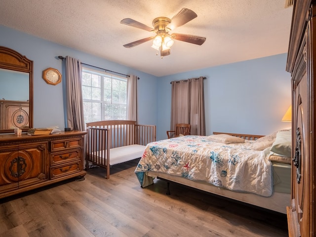 bedroom featuring ceiling fan, wood-type flooring, and a textured ceiling