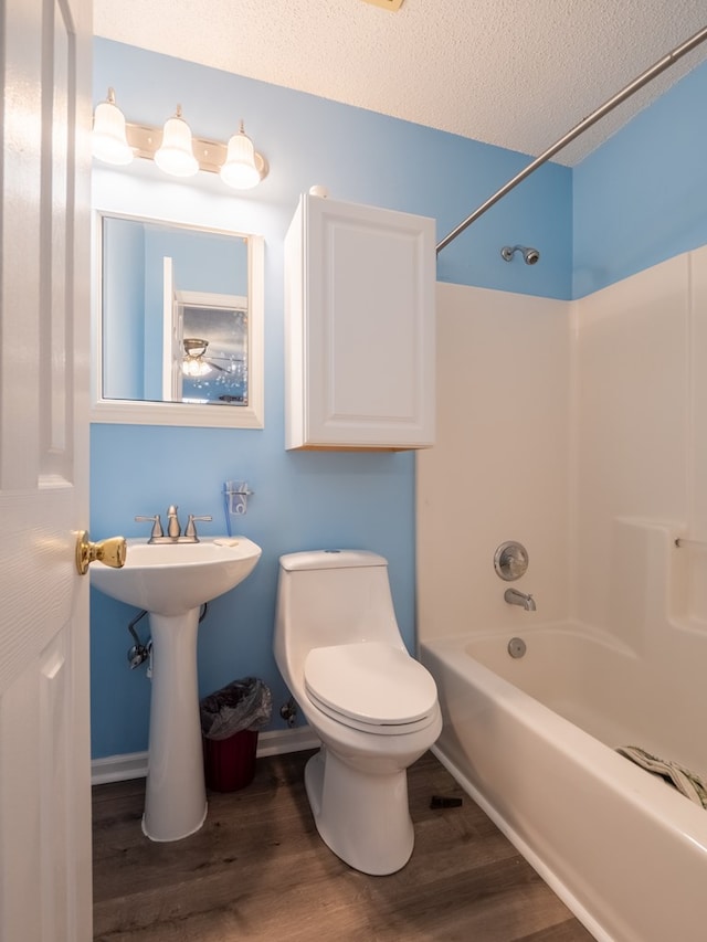 full bathroom with toilet, sink, a textured ceiling, shower / washtub combination, and hardwood / wood-style flooring