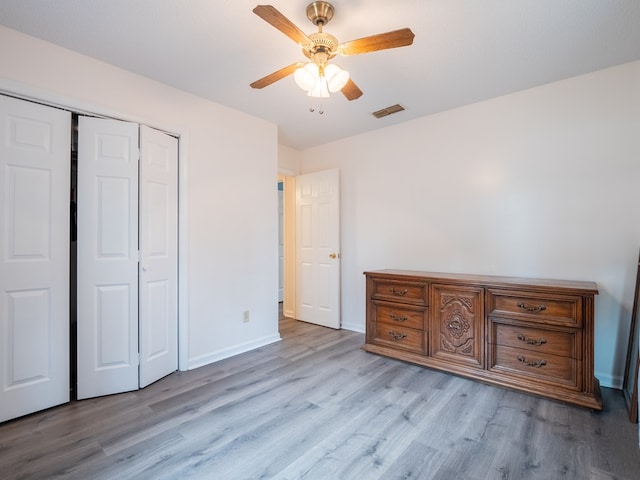 unfurnished bedroom with ceiling fan, a closet, and light wood-type flooring