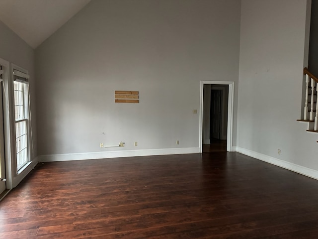 unfurnished living room with dark wood-type flooring and high vaulted ceiling