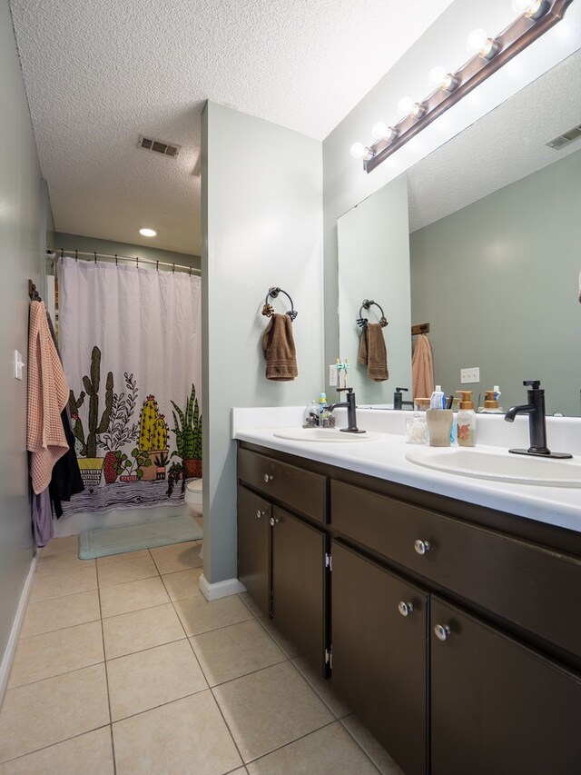 bathroom featuring a textured ceiling, vanity, tile patterned floors, and walk in shower