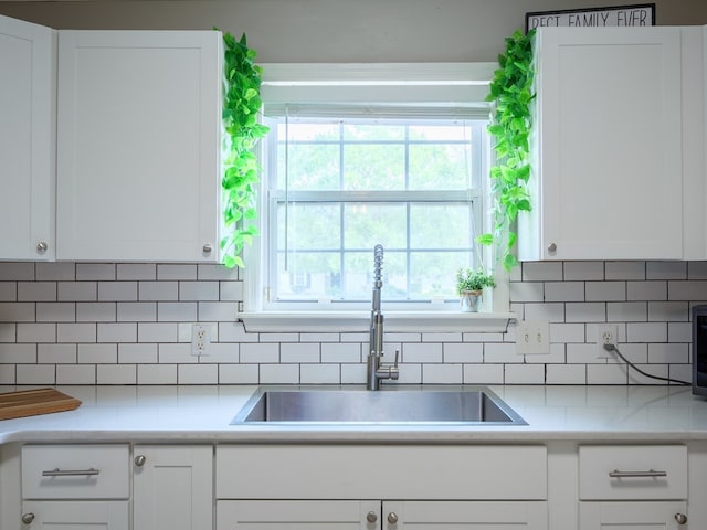 kitchen featuring white cabinetry, sink, and tasteful backsplash