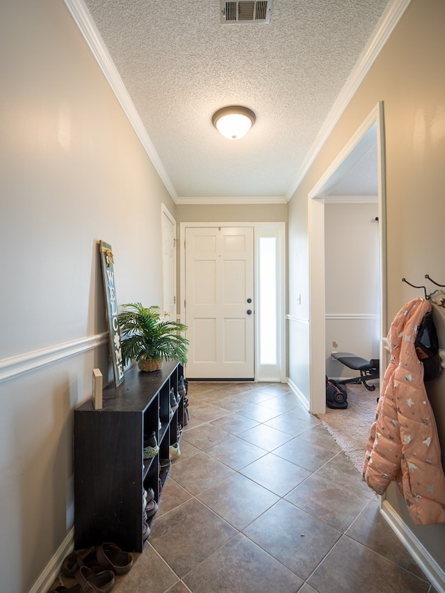 entryway with a textured ceiling, tile patterned floors, and ornamental molding