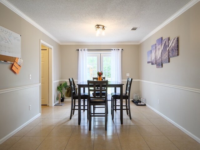 tiled dining space with a textured ceiling and crown molding