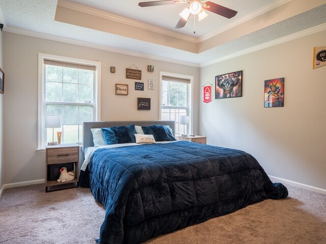 carpeted bedroom featuring a raised ceiling, ceiling fan, and ornamental molding