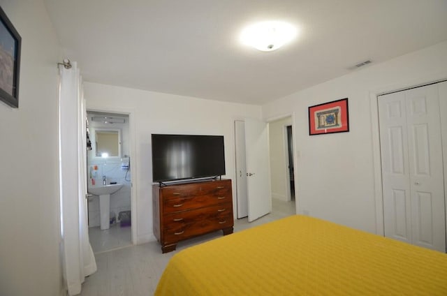 bedroom featuring connected bathroom, light hardwood / wood-style floors, and a closet