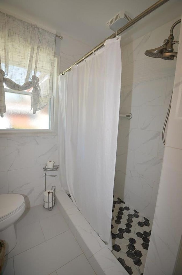 bathroom with curtained shower, tile walls, and toilet