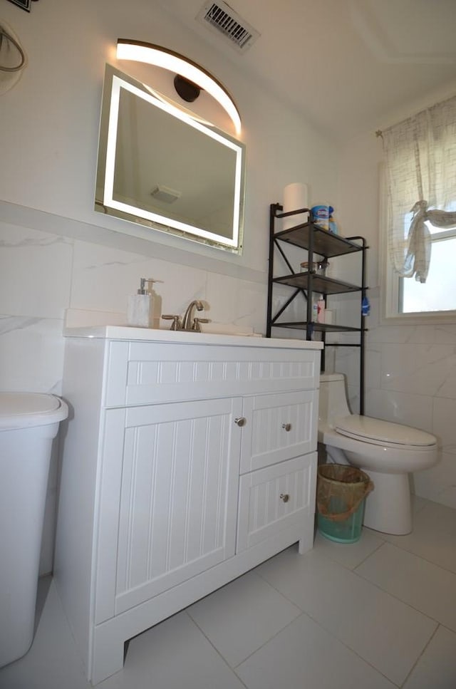 bathroom featuring vanity, tile walls, and toilet