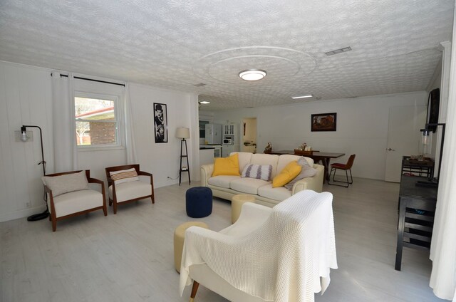 living room with a textured ceiling and light wood-type flooring