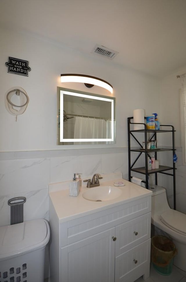 bathroom featuring vanity, toilet, curtained shower, and tile walls