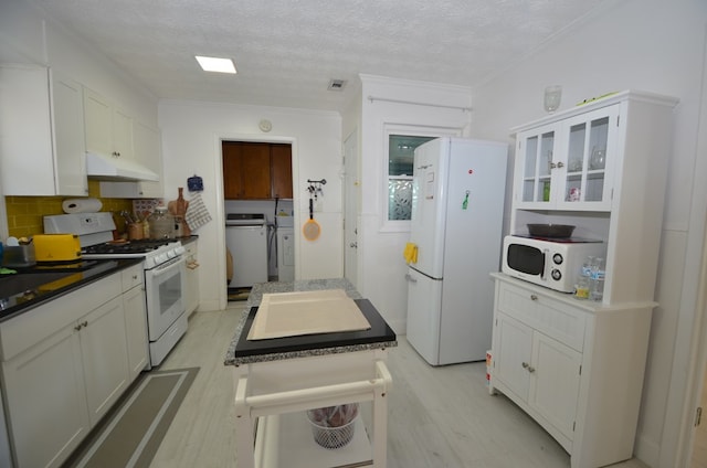 kitchen with white cabinetry, separate washer and dryer, backsplash, white appliances, and light wood-type flooring