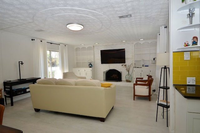 living room with a fireplace, a textured ceiling, and light wood-type flooring