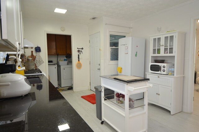 kitchen with white cabinetry, crown molding, washer and dryer, and light hardwood / wood-style flooring