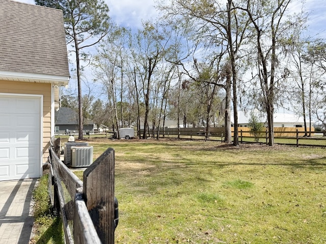 view of yard featuring a garage, cooling unit, and fence