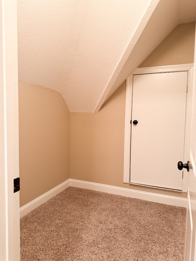 bonus room with a textured ceiling, vaulted ceiling, carpet, and baseboards