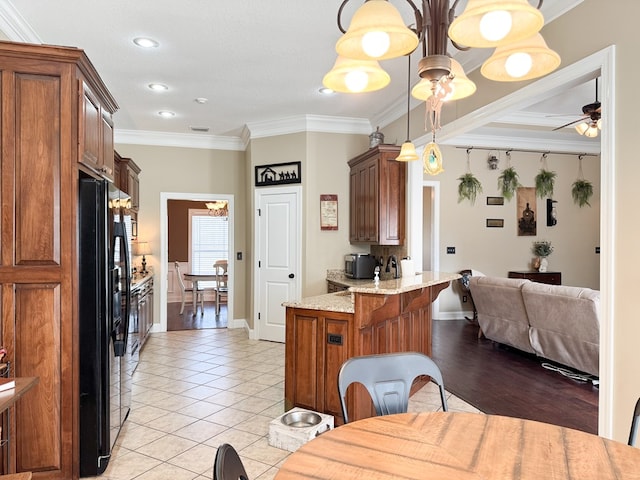 kitchen featuring a peninsula, light tile patterned flooring, ornamental molding, and black fridge with ice dispenser