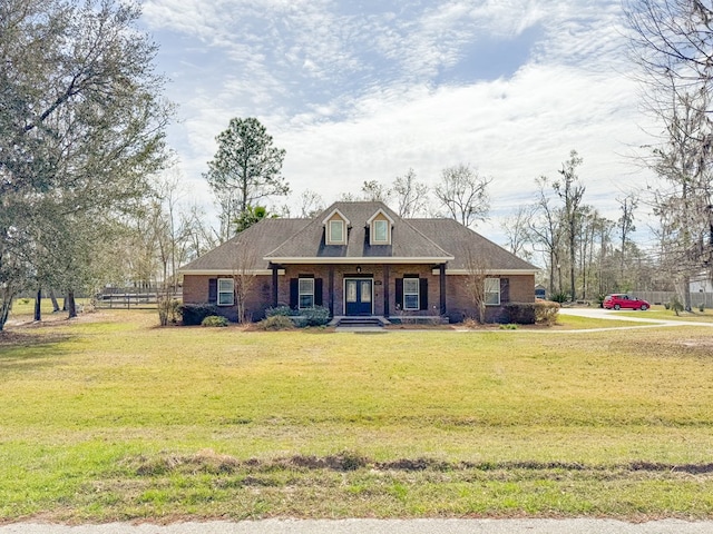 view of front facade with brick siding, fence, covered porch, and a front yard