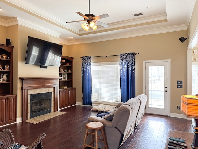 living room featuring dark wood-style flooring, plenty of natural light, a raised ceiling, and visible vents