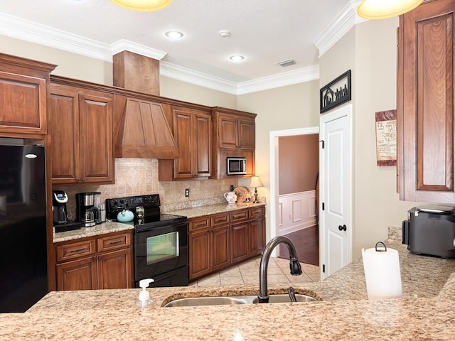 kitchen featuring decorative backsplash, ornamental molding, black appliances, premium range hood, and a sink