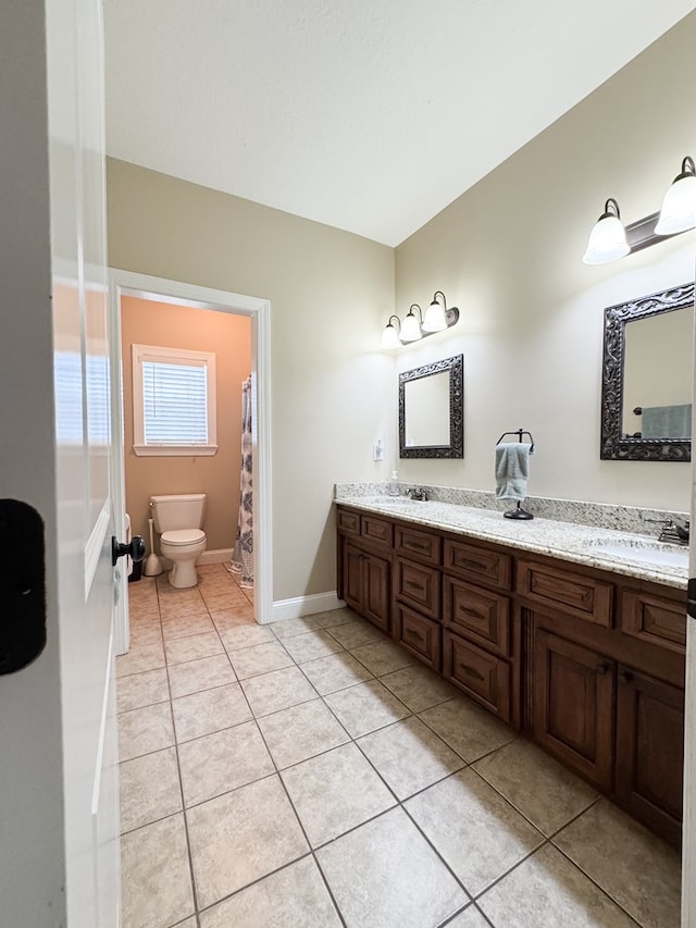 bathroom with toilet, double vanity, baseboards, and tile patterned floors