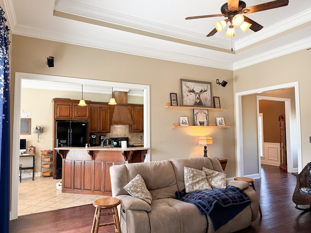 living room with crown molding, a raised ceiling, dark wood finished floors, and ceiling fan