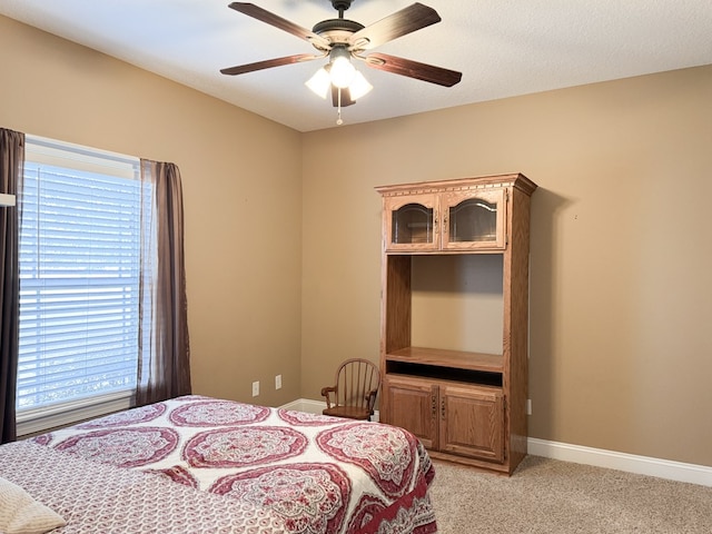 bedroom with light carpet, ceiling fan, a textured ceiling, and baseboards