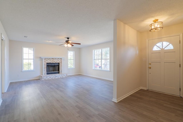 foyer entrance with a brick fireplace, dark wood-type flooring, and a textured ceiling