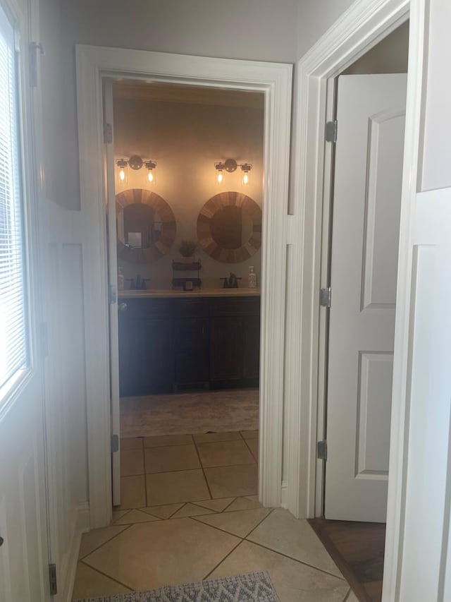 hall with tile patterned flooring, plenty of natural light, and a sink