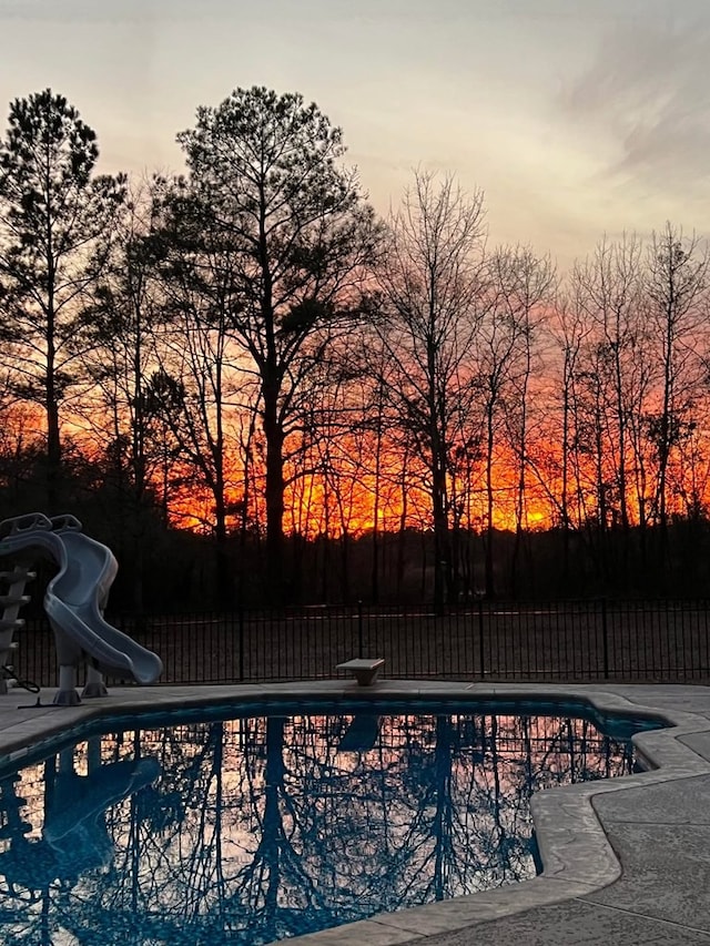 view of pool featuring a diving board, a fenced in pool, a water slide, and fence