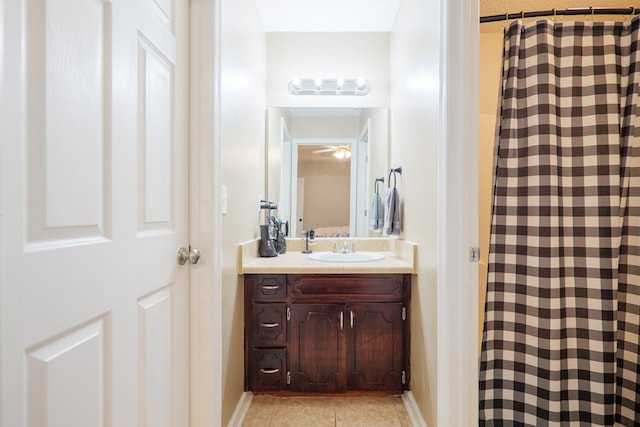 bathroom featuring a shower with shower curtain, tile patterned floors, baseboards, and vanity