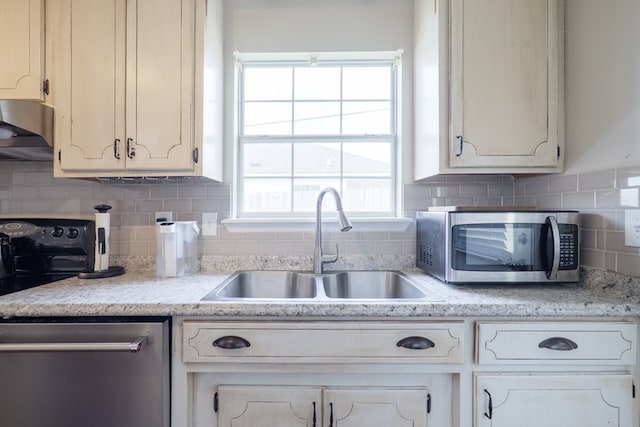 kitchen featuring appliances with stainless steel finishes, a sink, ventilation hood, light countertops, and tasteful backsplash