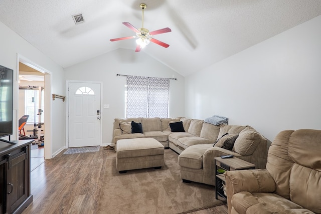 living area featuring vaulted ceiling, a ceiling fan, wood finished floors, and visible vents