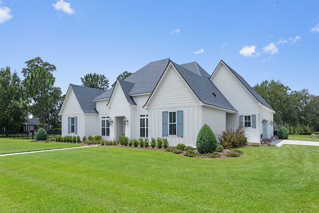 view of front of property featuring board and batten siding, a shingled roof, and a front yard