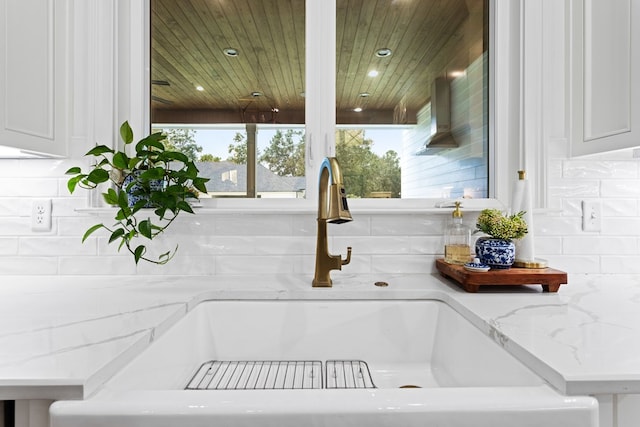 interior details with white cabinets, recessed lighting, a sink, light stone countertops, and tasteful backsplash