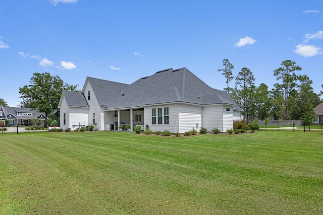 back of house with fence, a shingled roof, and a yard