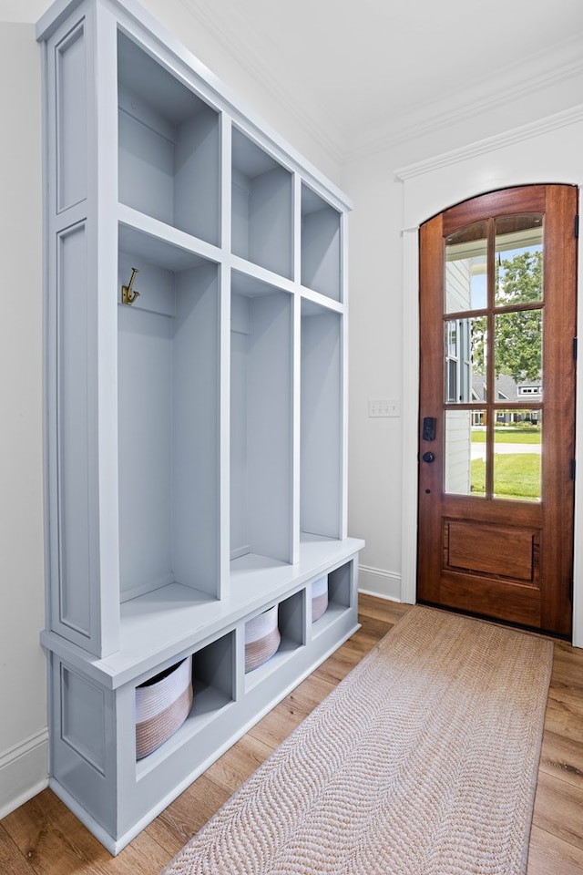 mudroom with wood finished floors, crown molding, and baseboards