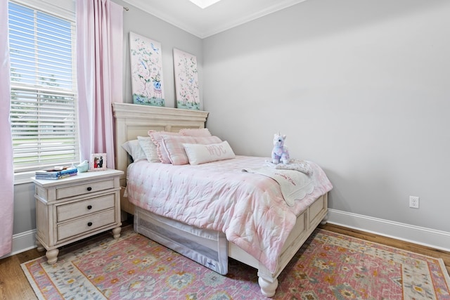 bedroom featuring wood finished floors, baseboards, and multiple windows